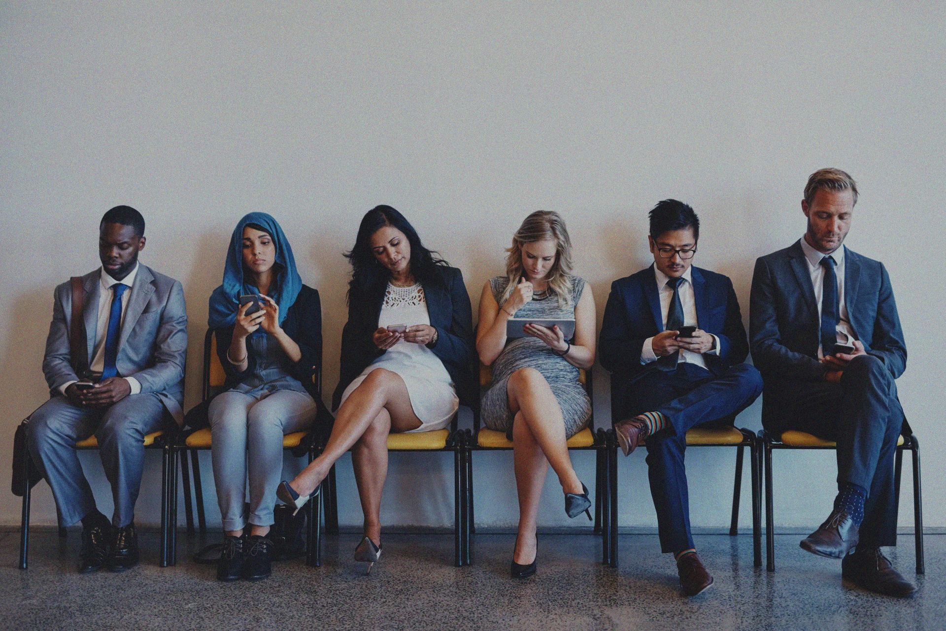 Businesspeople sat observing their tablets and phones