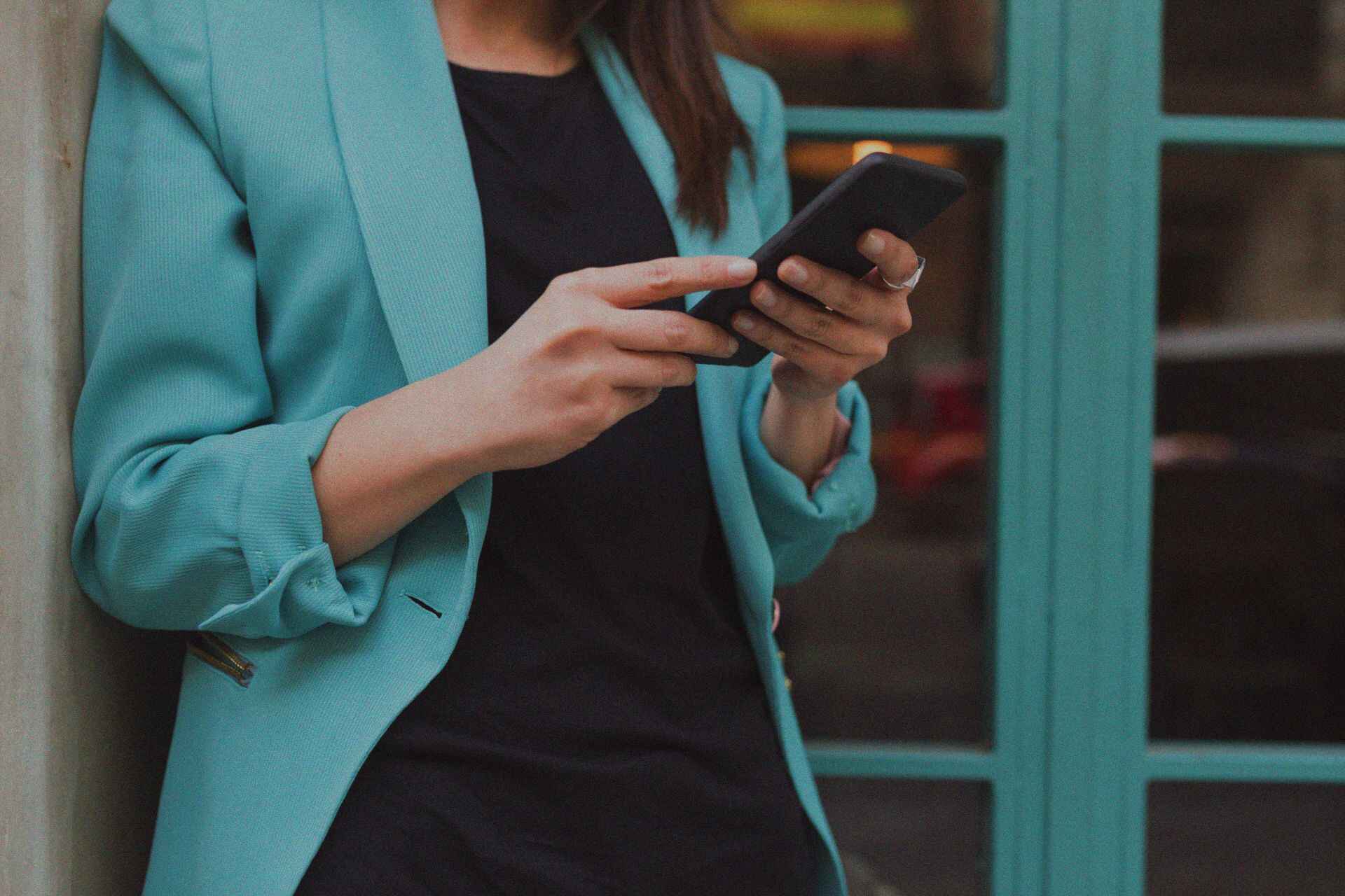 A businesswoman in a turquoise suit using her laptop