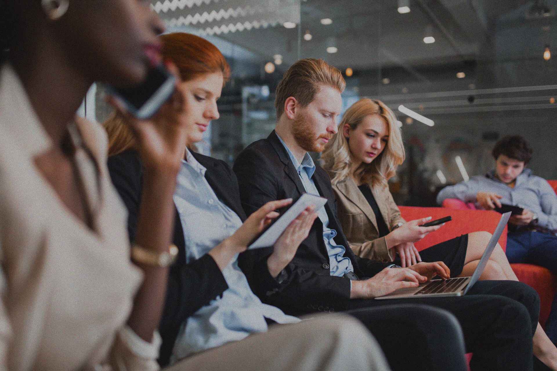 Businesspeople sat observing their tablets and phones